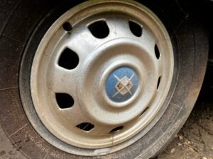An original Airstream hubcap, dusty, on the trailer's wheel