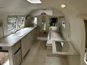 Inside the trailer: white-painted walls, a sink and long counter, cabinets and a mirror