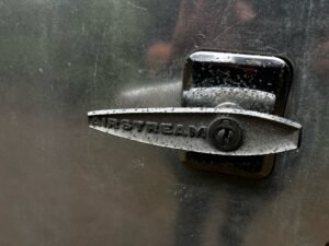 The chrome Airstream door latch, beaded with rain